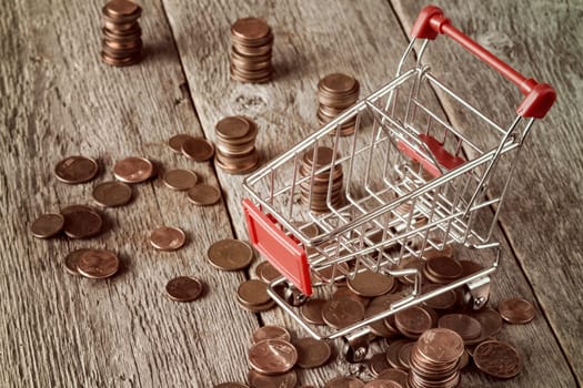 Shopping cart with coins on wooden background. Retail,sale or marketing concept