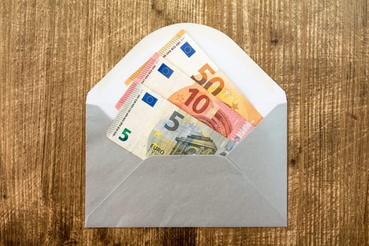 Silver envelope with Euro currency over wooden background