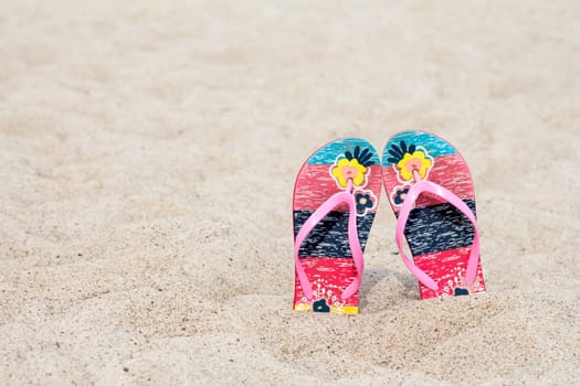 Flip flop on the sand beach in summer vacations. Copy-space.