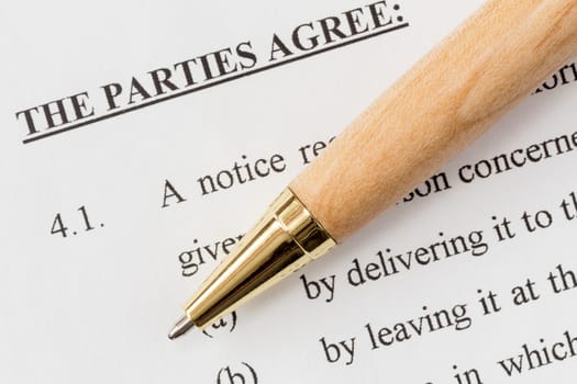 Wooden pen over a printed agreement