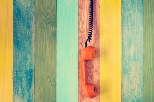 Hanging the phone handset on the color wooden wall background