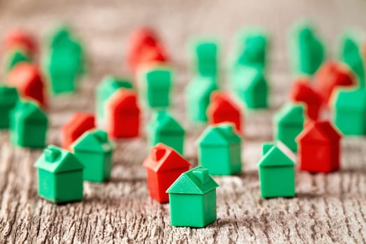 Red and green plastic toy houses on a wooden background.Real estate concept.