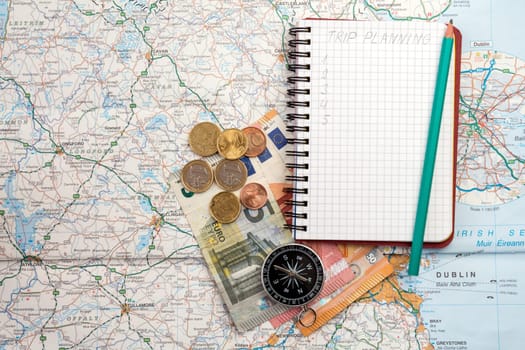 Travel concept with notebook written TRIP PLANNING , compass and money on the  map