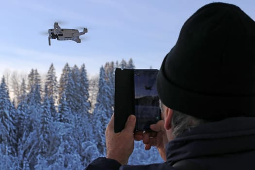 A man takes a picture of a flying drone with his smartphone