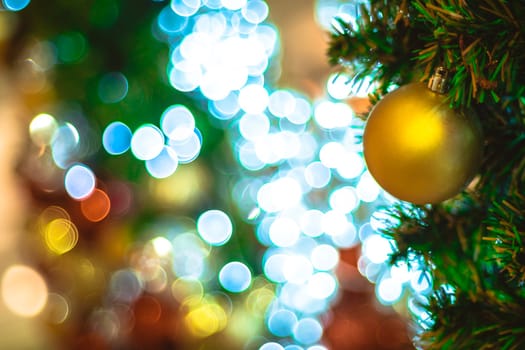 Selective focus Christmas tree with holiday gold ball and lights with copy space on blurred bokeh background.