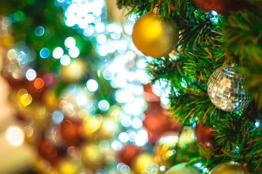 Selective focus Christmas tree with holiday silver disco balls and gold ball and lights with copy space on blurred bokeh background.