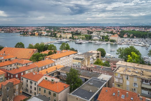 Drone or birds eye view on orange tiled roofs and cityscape of Zadar. Bay or marina with moored yachts and boats, Croatia