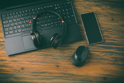 Working place and office desk with laptop, headset, smarthpone and computer mouse, wooden background