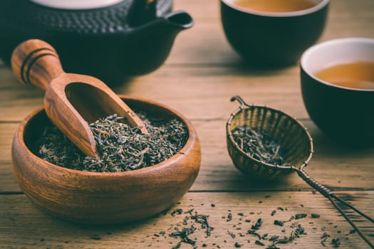 Black tea with dried tea leaves and infuseron wooden background