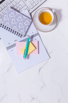 Flat lay home business desk - cup of tea, with communication device with and writing tools. Feminine business mockup, copyspace, white background.