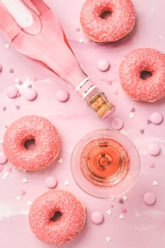 Rose wine or cocktail with pink donuts and pink chocolate beans on pink background