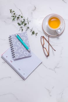 Flat lay home business desk - cup of tea, with communication device with and writing tools. Feminine business mockup, copyspace, white background.