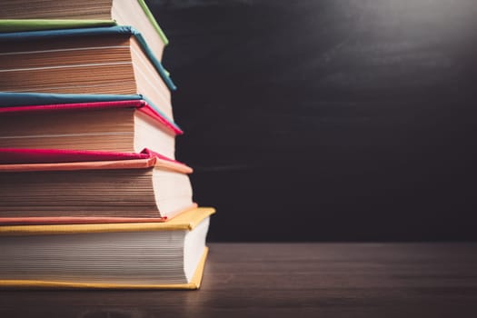 school accessories on the table with blackboard background. Stack of the books