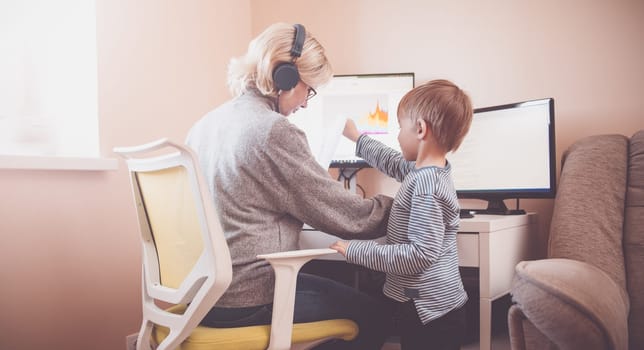 Woman working at home with little child. Young businesswoman working indoors at pc