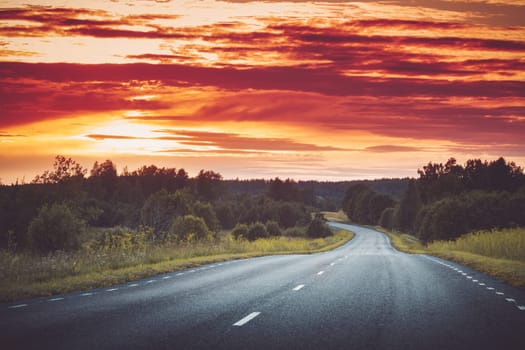 Beautiful road panorama on sunny spring evening. Asphalt way view in countryside at the sunset