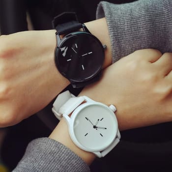 Time reconciliation on the wristwatch. White and black watches.