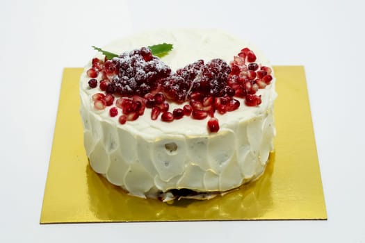 Cake sprinkled with pomegranate berries. Cake on a white background.