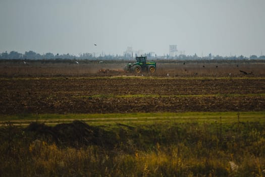 The tractor plows the field with a plough. Ploughing the soil.