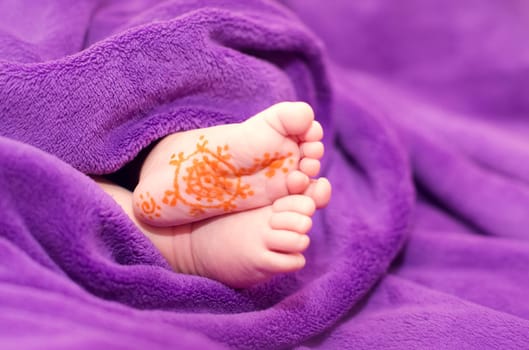 The baby's legs are from under the blanket. On the leg painted a pattern marker.
