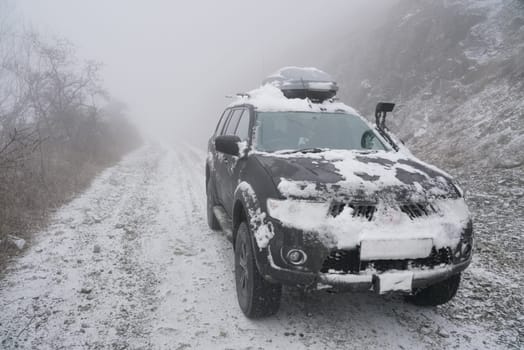 SUV on the rise of snow winter forest