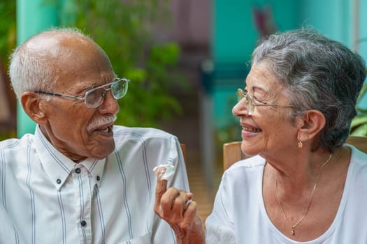 Elderly couple looking at each other smilingly and the woman with a finger with cake meringue