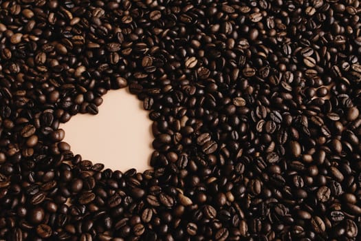 Background with array of dry coffee beans with heart shape. Beige. High quality photo