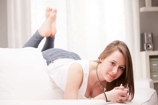 young happy brunette lying on a couch in her living room
