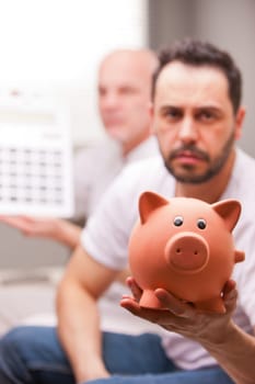a couple of men with economic problems showing up a piggybank and a calculator