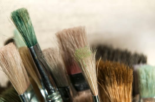 Bunch of various used paintbrushes on canvas background