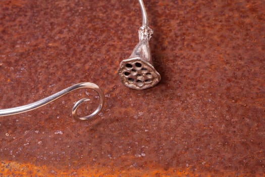 Close up of silver necklace on rusty iron, manufactured by Ornella Salamone