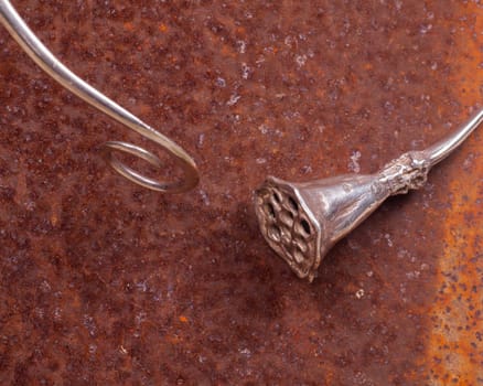Close up of silver necklace on rusty iron, manufactured by Ornella Salamone