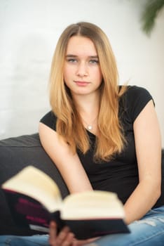 Young blonde girl sits at home and reads
