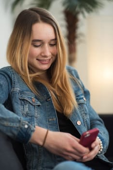 Girl sits on a sofa and simst with smartphone