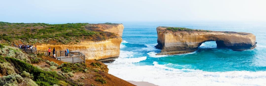 Port Campbell National Park, Victoria state, Australia - February 19, 2015: Tourists visiting the London Bridge at Twelve Apostles, a famous collection of limestone stacks off the shore of the Port Campbell National Park, by the Great Ocean Road in Victoria, Australia