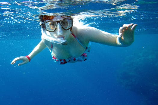 A woman snorkels in the sea. Snorkeling woman in the Red Sea. A woman with diving goggles underwater.