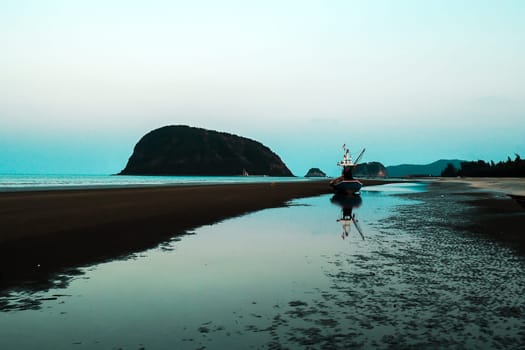 A man walking alone on the beach on holiday at KhaoSamroiyou Prachubkeereekhan Thailand .lonely alone concept idea.walking mediatation with nature concept. silhouette mountain  and reflection on scene.beautiful moment