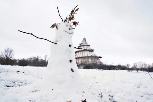 Snowman on a meadow in Magdeburg. In the background the millennium tower.