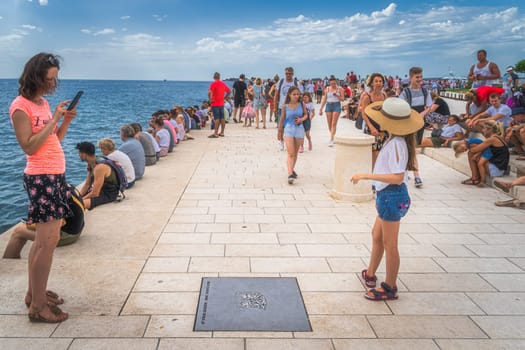 Zadar, Croatia, July 2019 Crowd of tourists listen to Sea organ, Morske orgulje, sound art object which plays music by way of sea waves and tubes