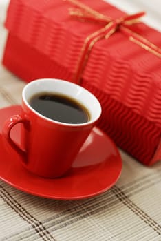 Close-up of a cup of black tea on a saucer with a gift