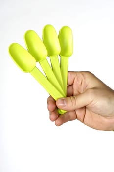 Close-up of a personŽs hand holding four plastic spoons