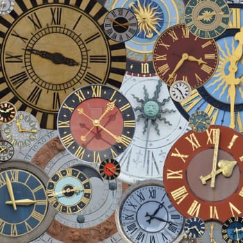 multicolored collection of ancient church tower clocks on a pile in different sizes and forms with roman numbers