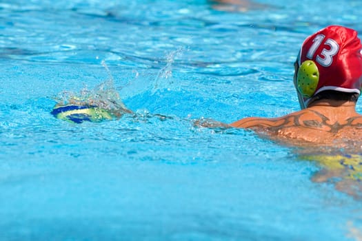 Rear view of a mid adult man playing water polo in a swimming pool