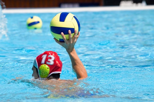 Rear view of a mid adult man playing water polo in a swimming pool