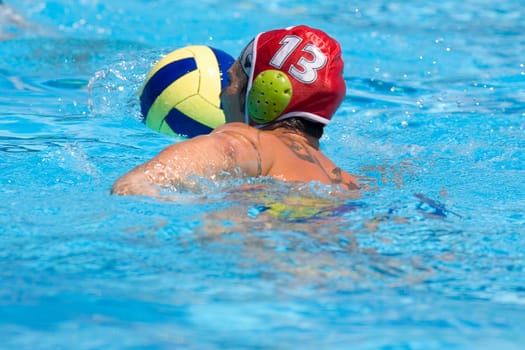 Rear view of a mid adult man playing water polo in a swimming pool