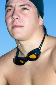 Close-up of a young man wearing swimming goggles around his neck