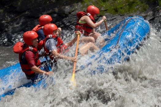 Side profile of four people rafting in a river