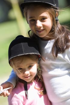Close-up of two girls wearing riding hats and smiling