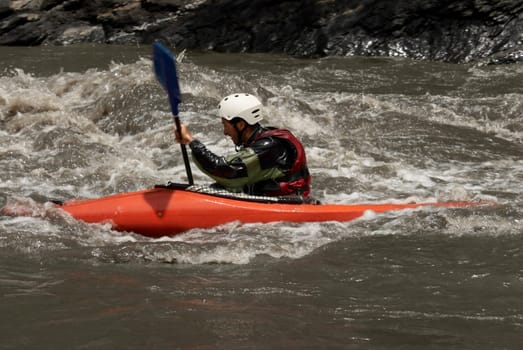 Side profile of a young man kayaking in a river