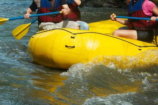 Mid section view of three people rafting in a river