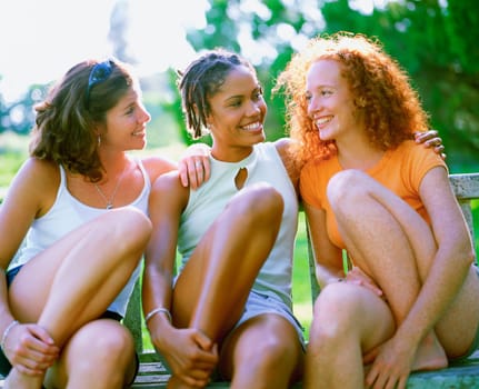 Close-up of three young women sitting on a bench and smiling, Bermuda